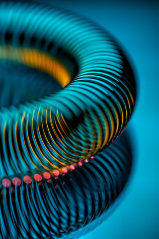 Close-up of a coiled cocktail strainer with multicolored bands on a blue background